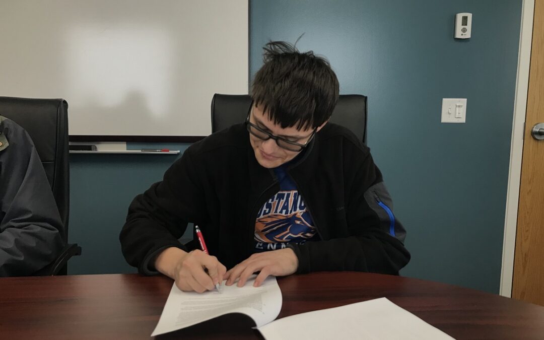A student signs a work agreement for a sponsorship through Golden Path Solutions.