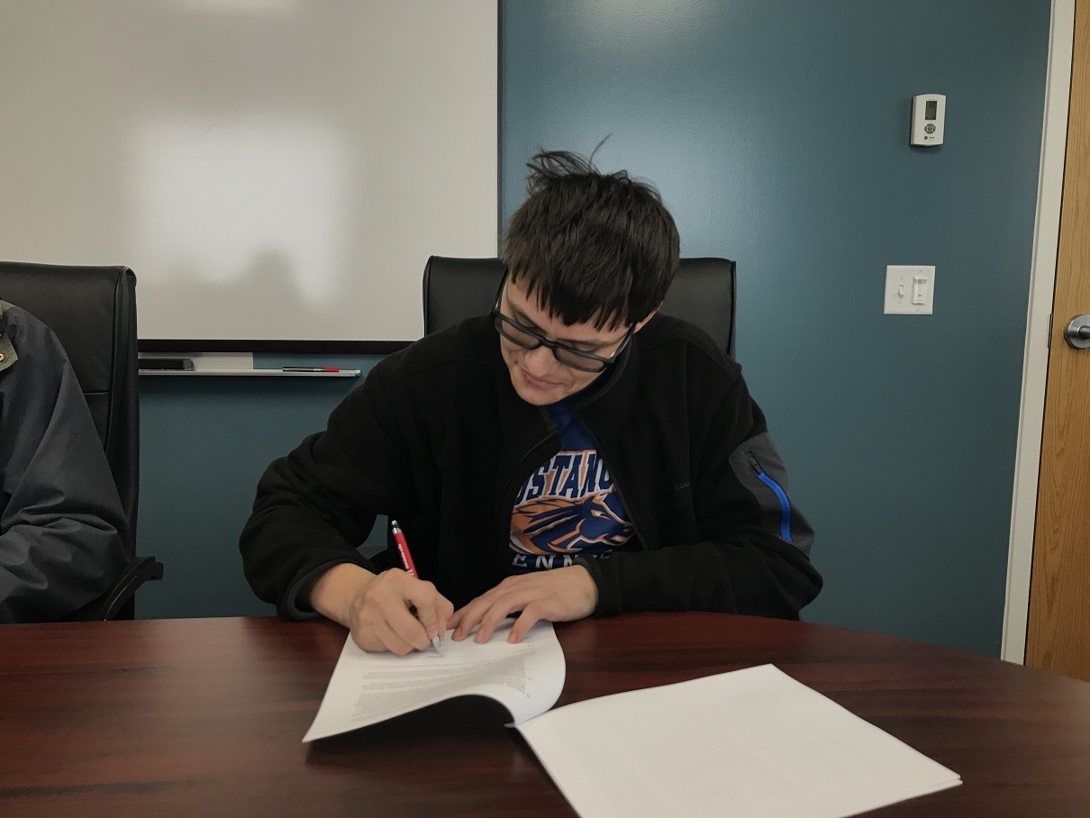 A student signs a work agreement for a sponsorship through Golden Path Solutions.