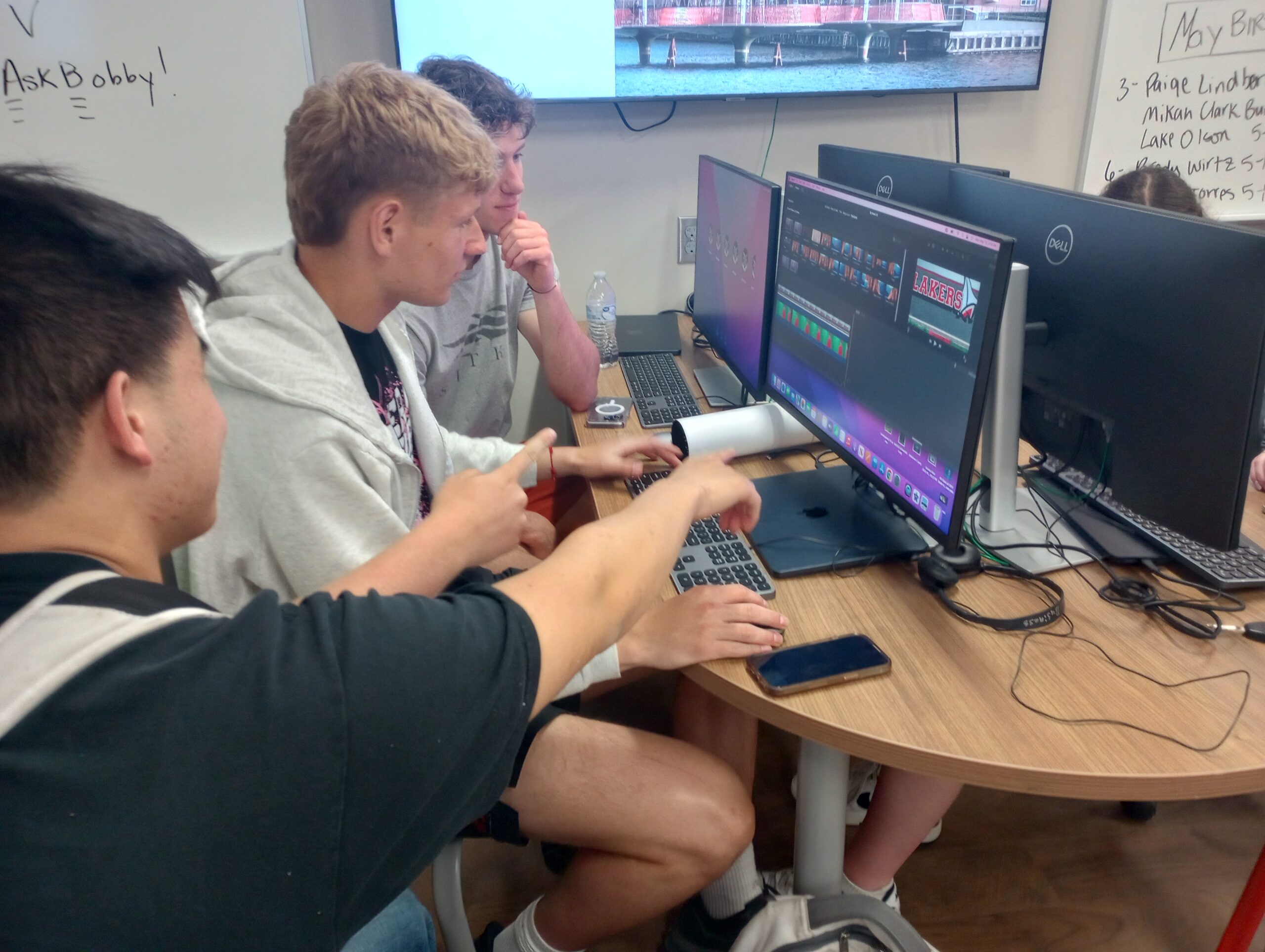 Three students work at a computer in a Detroit Lakes High School lab, finishing a project for the year.