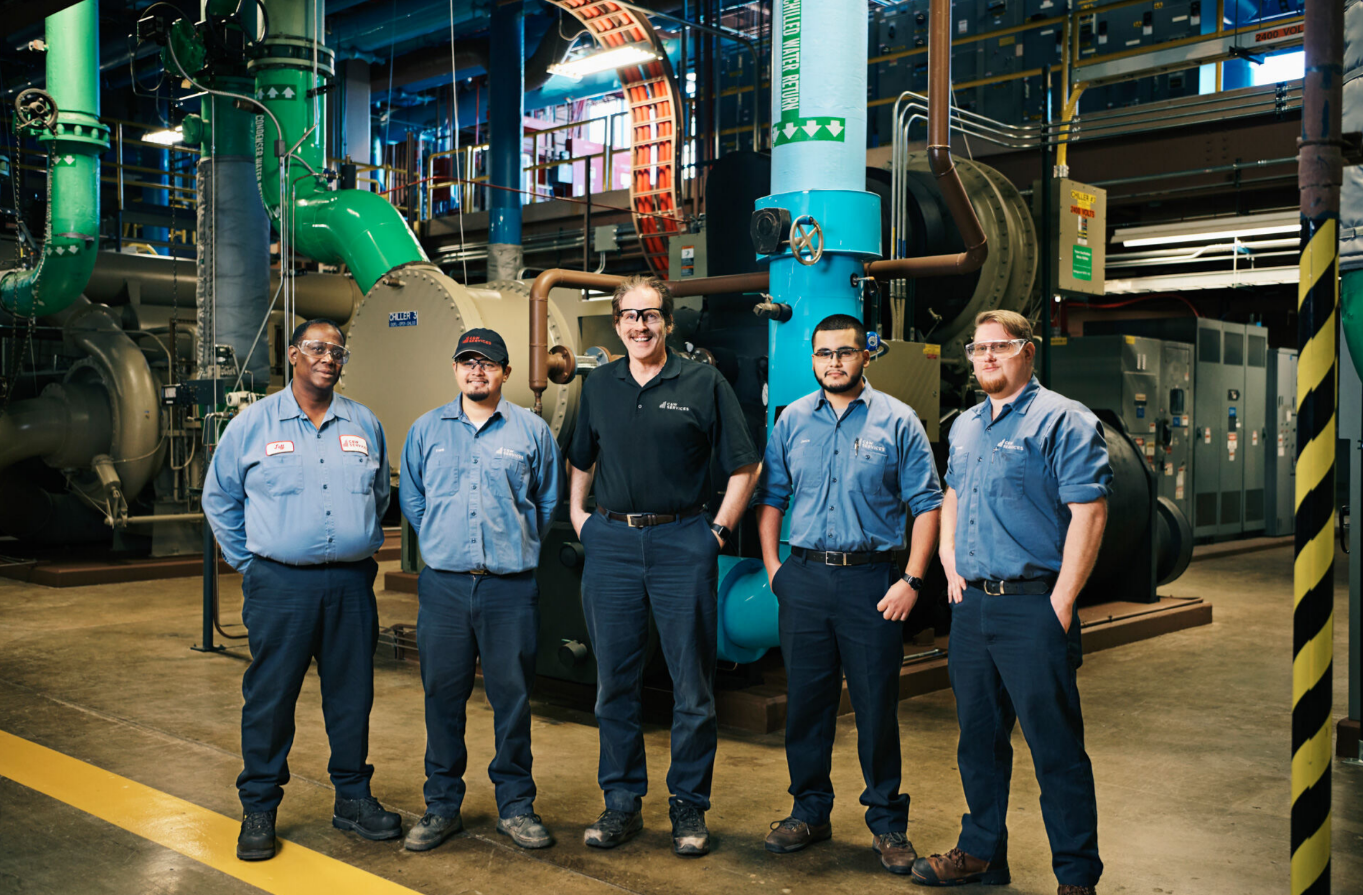 five C&W Services employees stand together in their workplace