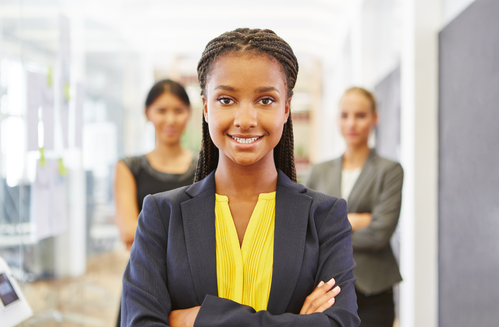 A female student stands in front of two other female workers