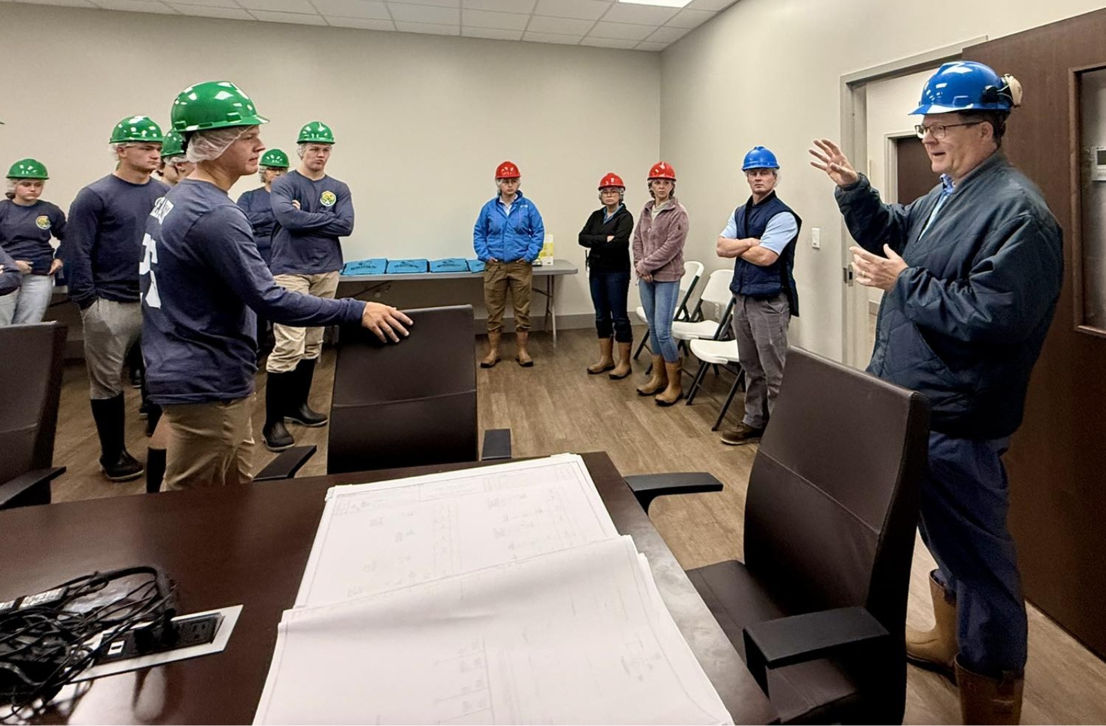 Cherokee Chamber Leadership Blog Post A group of students wearing hardhats are in a classroom listening to an employer speak about his company