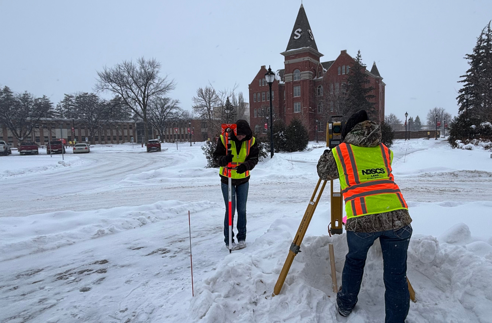 Two NDSC survey technology students practice with survey equipment outside on campus