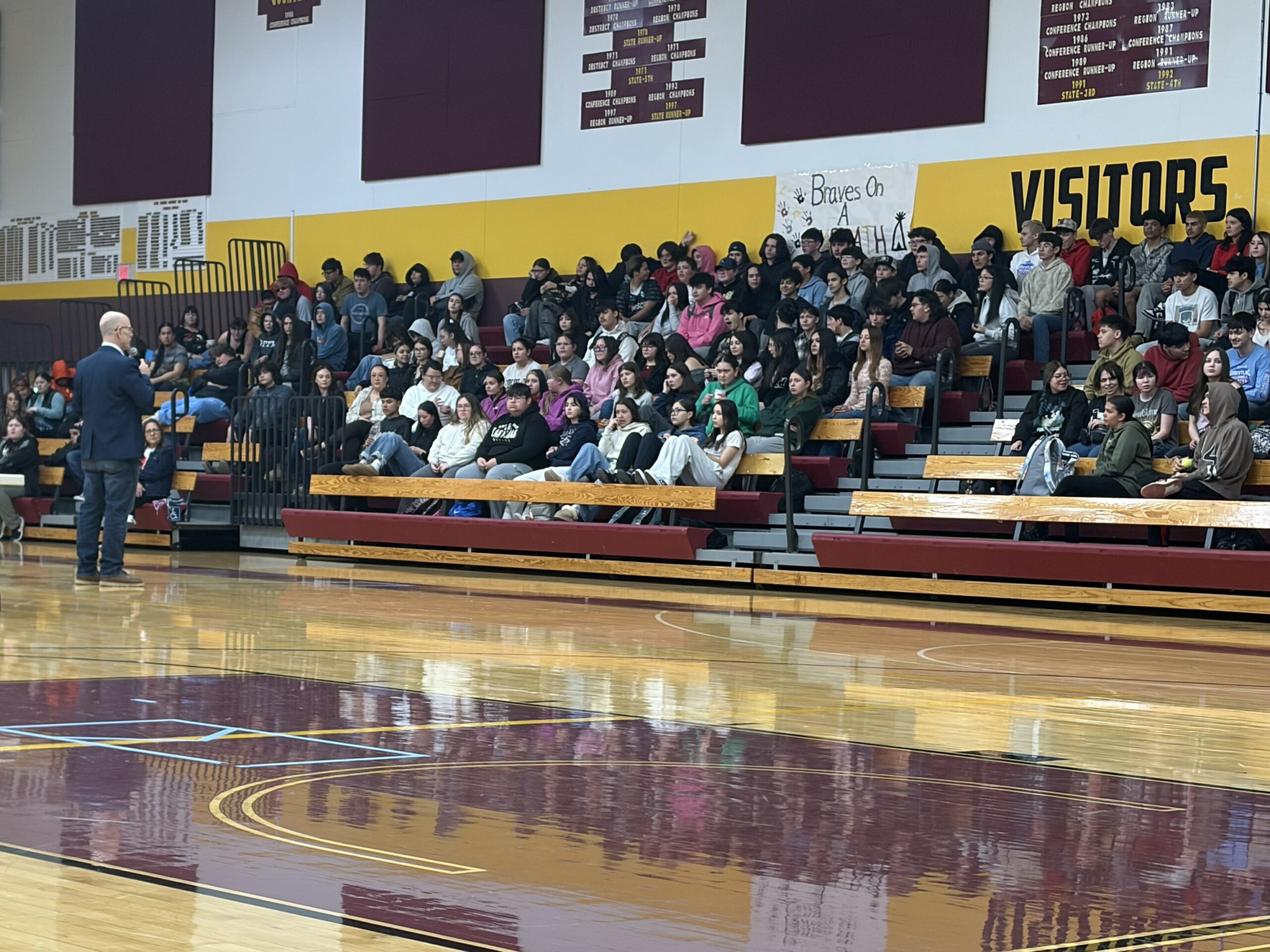A presenter addresses a crowd of students and families at a career event in Belcourt, ND